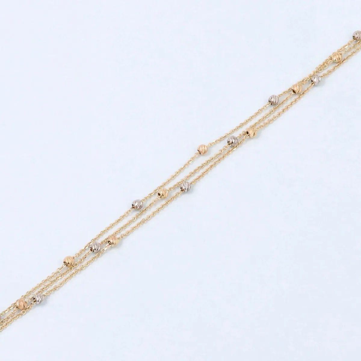 Lightweight three-row bracelet in white and yellow gold with diamond-cut beads